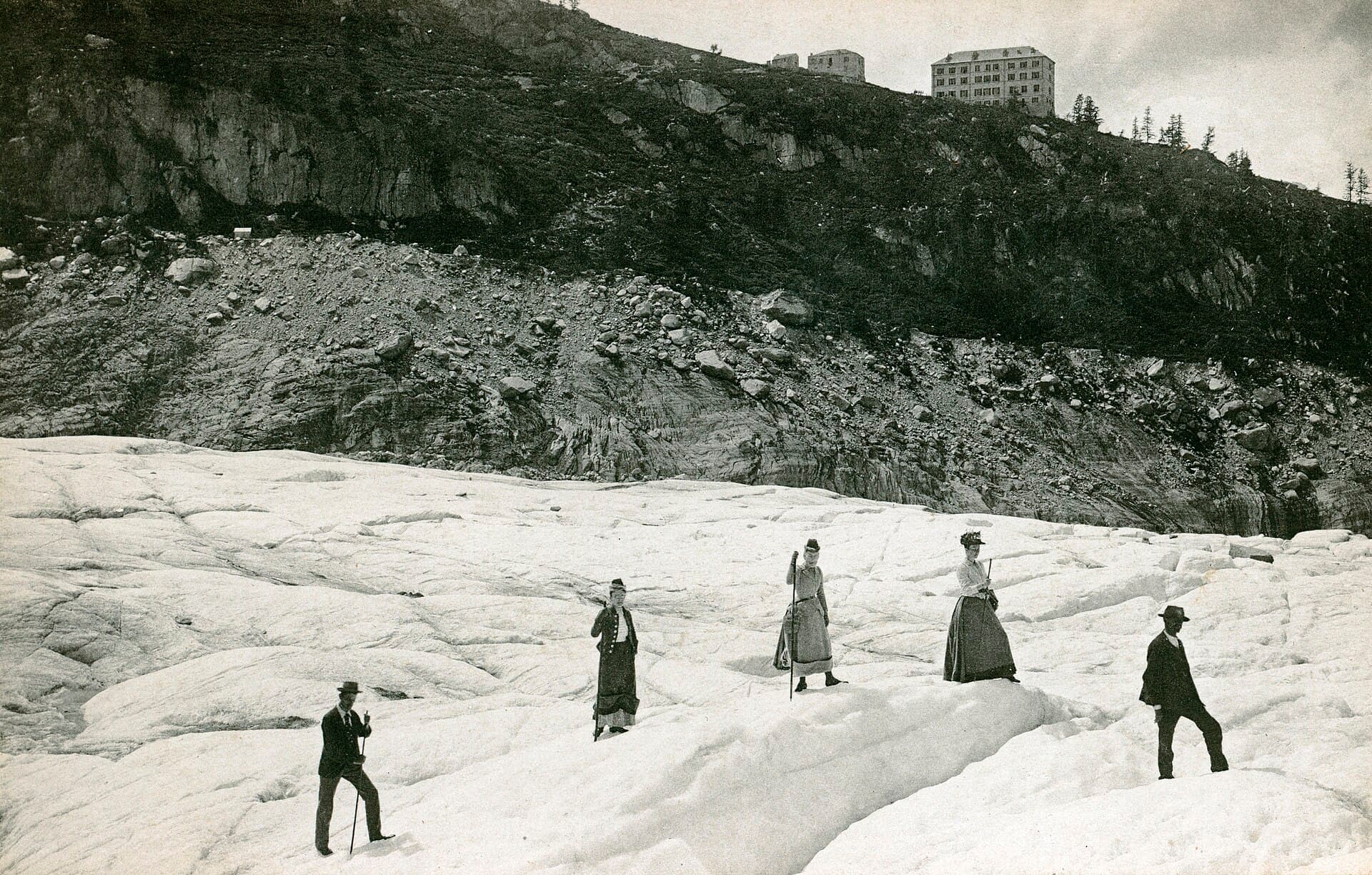 Visitors in period dress standing and walking on the Mer de Glace around 1900.