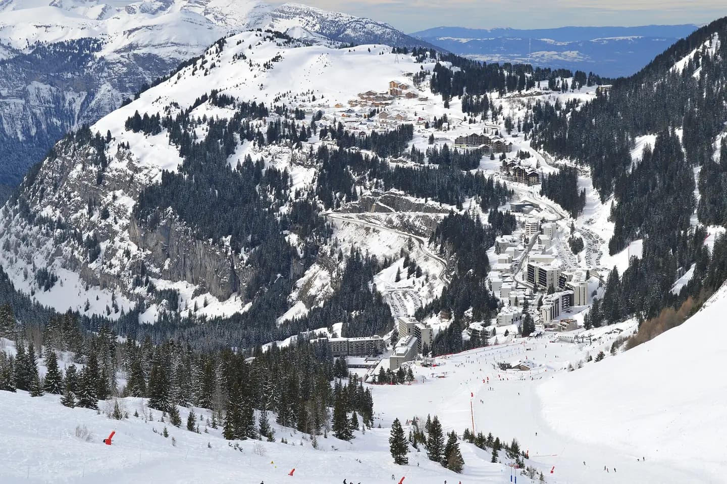 Overview of Flaine in Haute-Savoie, France, during winter sports season, with its neighborhoods Flaine Forum, Forêt, Montsoleil, and Le Hameau, seen from the ski slopes to the east of the town beneath Tête de Balacha