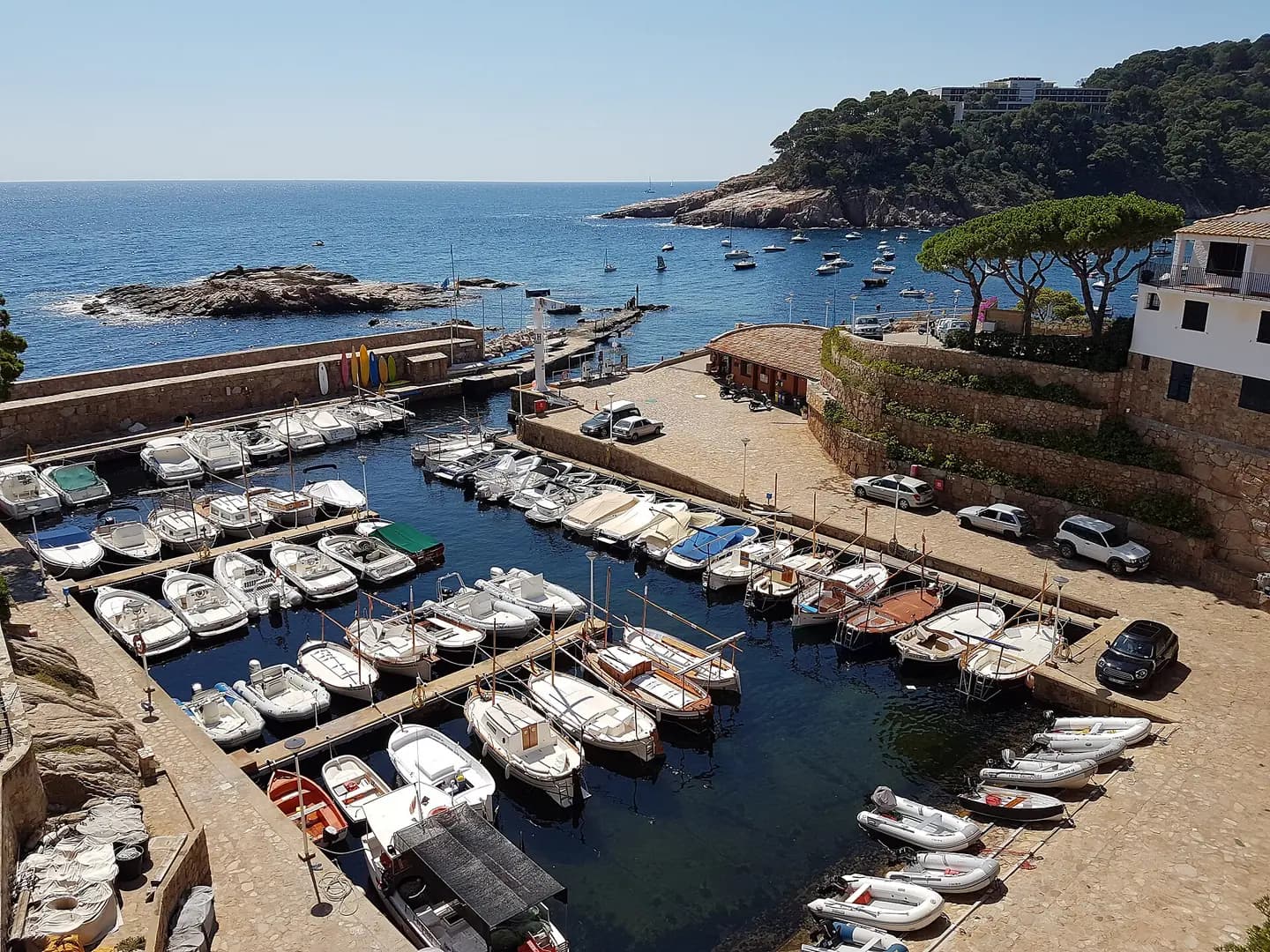 Boats moored in the marina at Fornells, Begur, Catalonia, Spain. The bay of Aiguablava is beyond, with the anchored boats
