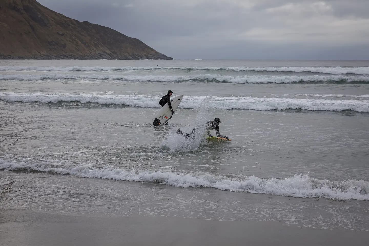 The photograph shows surfers at Hoddviksanden beach in Hoddevik on Stadlandet, Stad municipality, Vestland, Norway. The image documents surfing activity at the beach and the exposed coastal setting