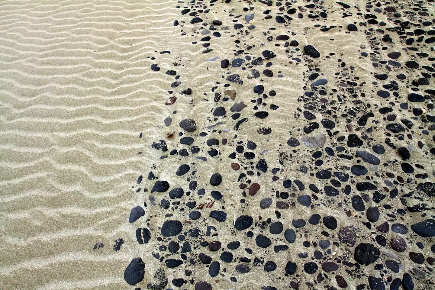 Detail to sand and rocks on the beach Playa de Famara on Lanzarote, the Canary Islands, Spain