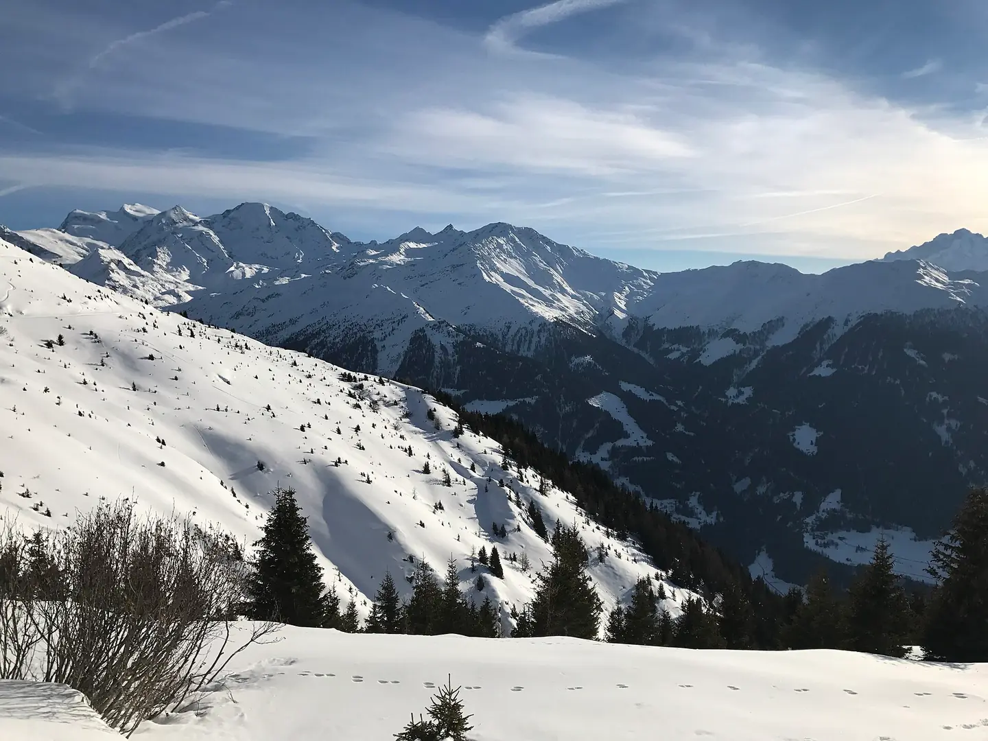 Footprints in snow in the foreground, with pristine snow and mountains in the background. Facing Southwest during winter