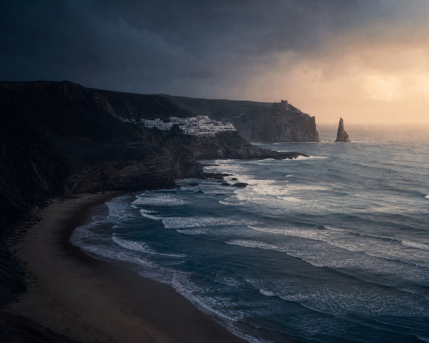 Arrifana's cliff village and black Pedra da Agulha above Atlantic surf