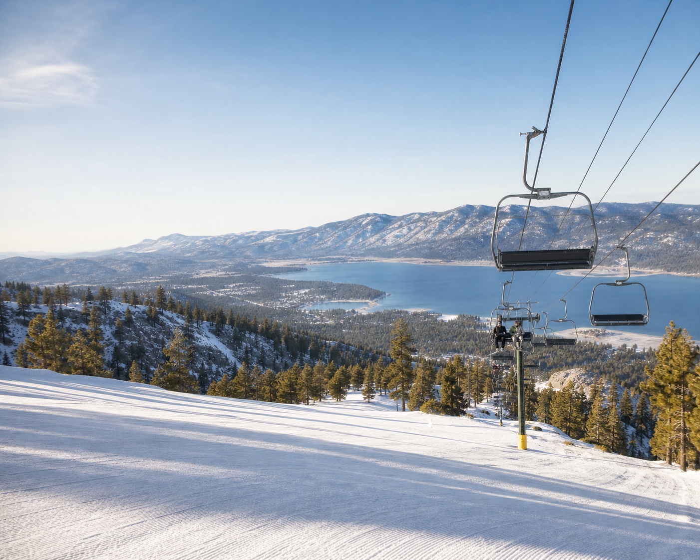 Big Bear chairlift above snowy pine forest and brilliant blue lake