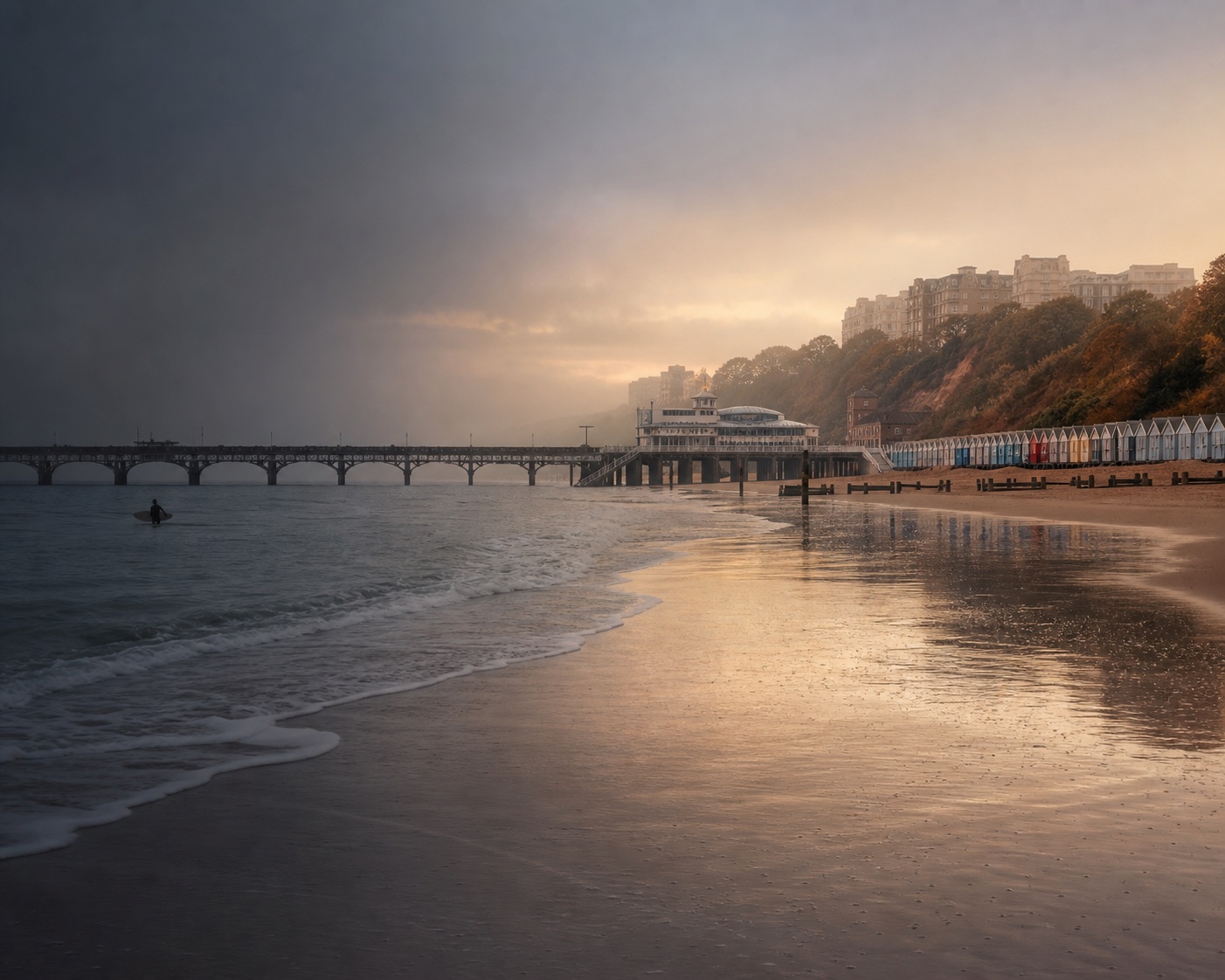 Bournemouth Pier and colourful beach huts above gentle Channel surf
