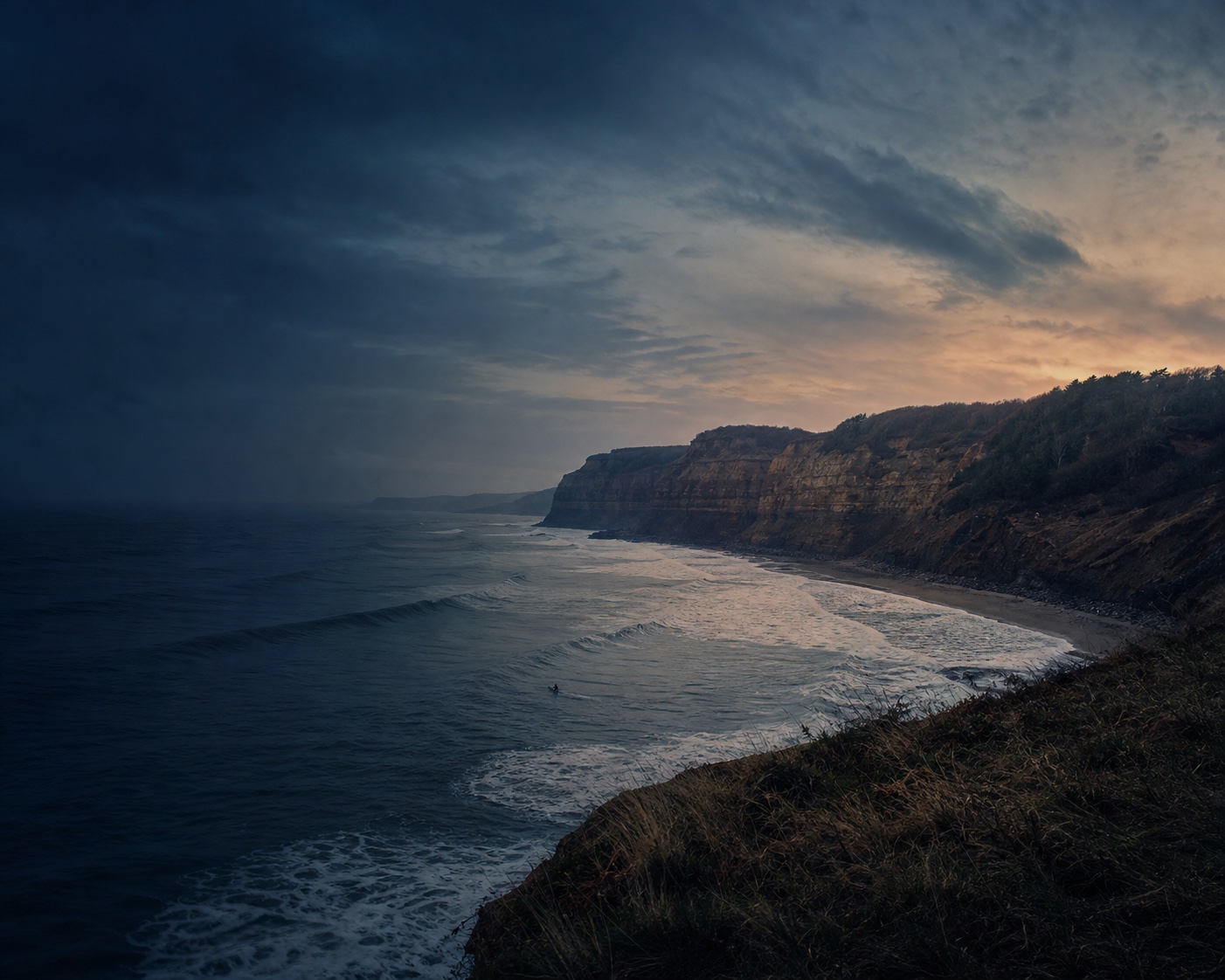 Cayton Bay surf sweeping beneath rugged Jurassic Coast cliffs