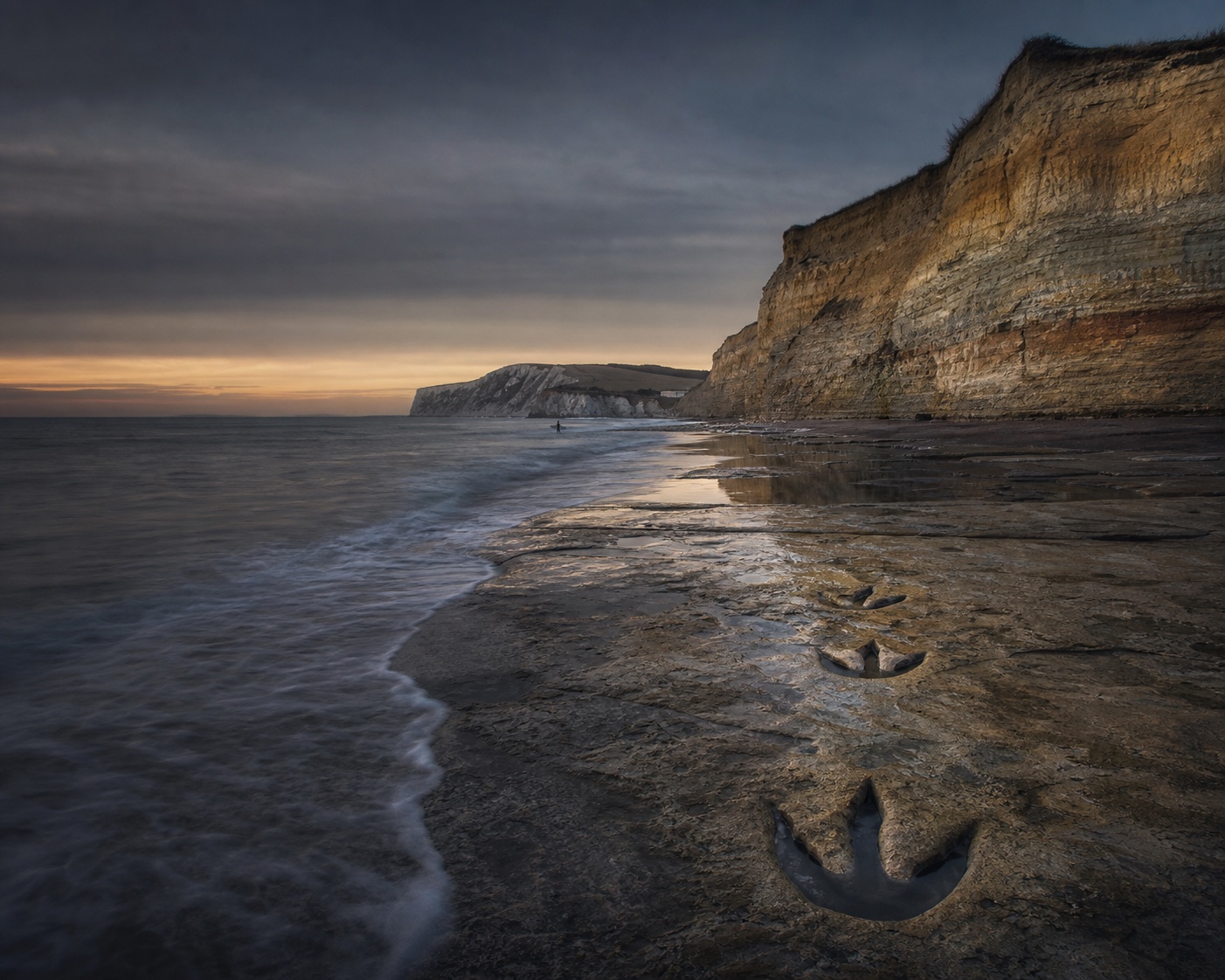 Compton Bay surf, layered fossil cliffs and dinosaur footprints at low tide