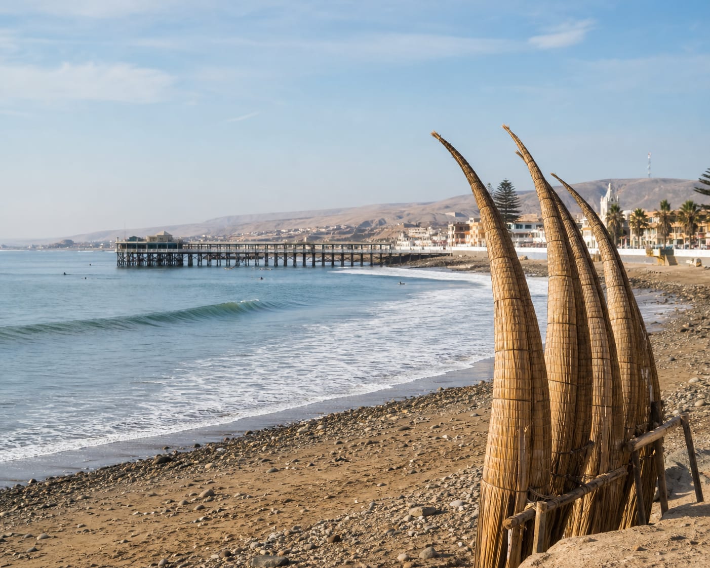 Huanchaco's reed caballitos de totora standing beside its historic pier
