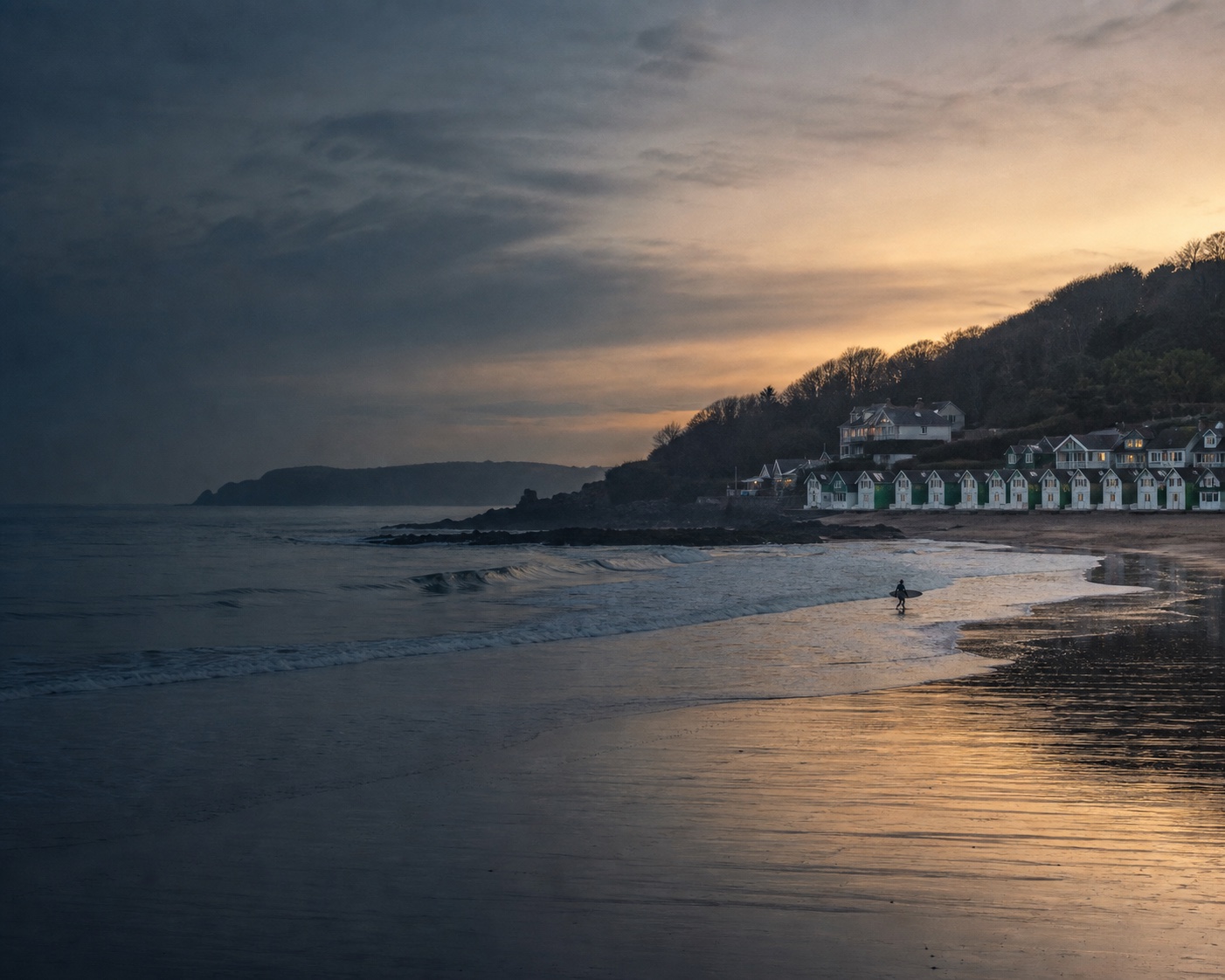 Langland Bay surf and its green-and-white beach huts at dawn