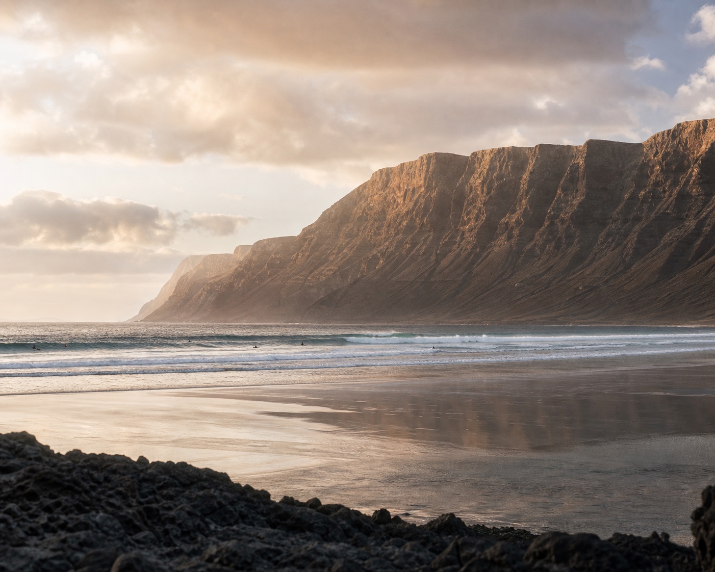 The immense Risco de Famara cliffs rising behind the beach and Atlantic surf