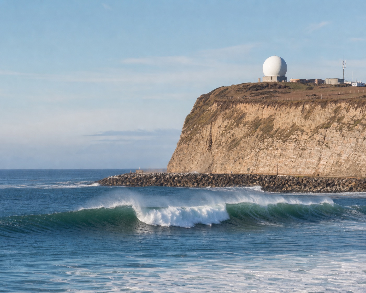 Mavericks breaking below Pillar Point bluff and its white radar dome