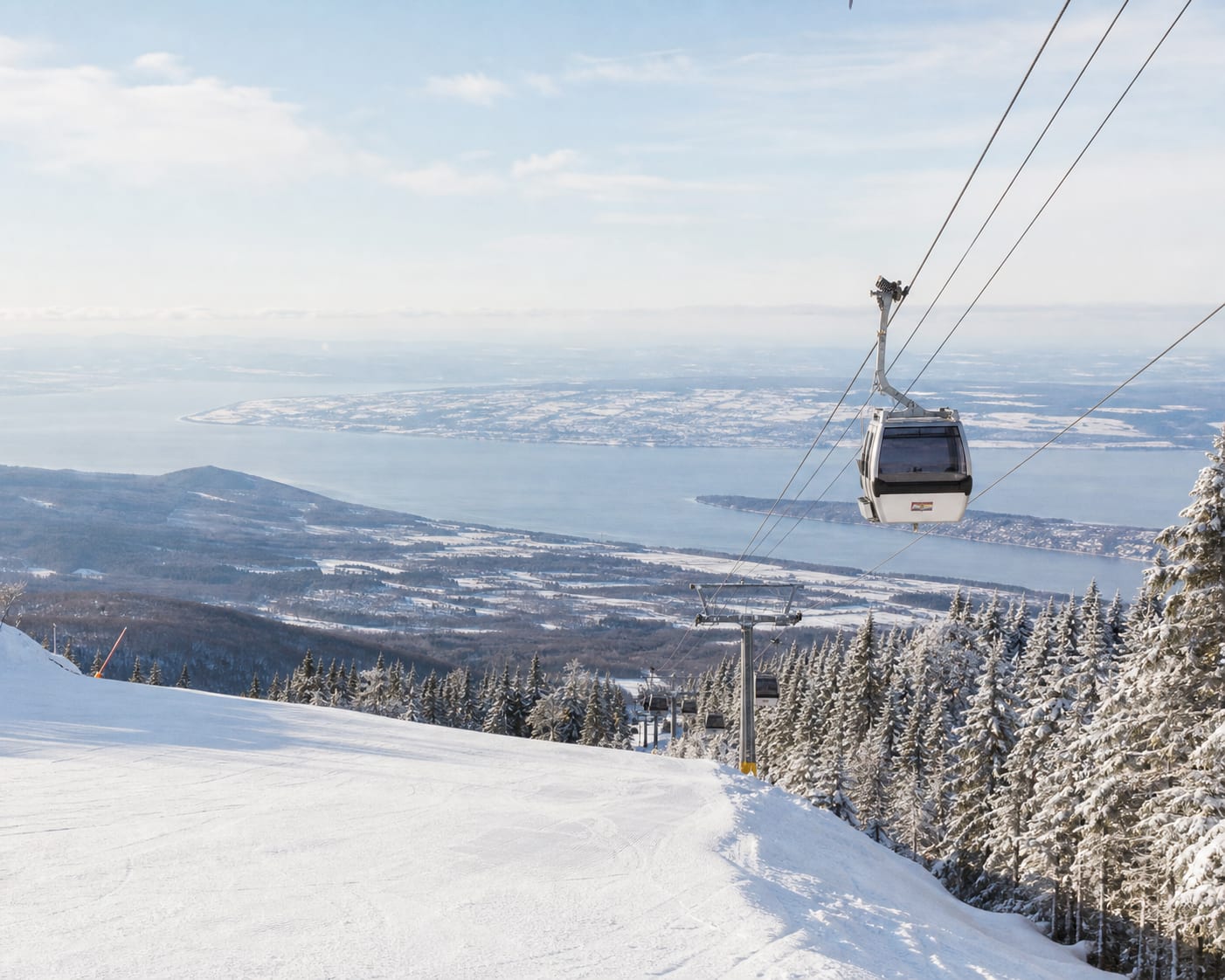 Mont-Sainte-Anne gondola above snowy forest with the St Lawrence River beyond