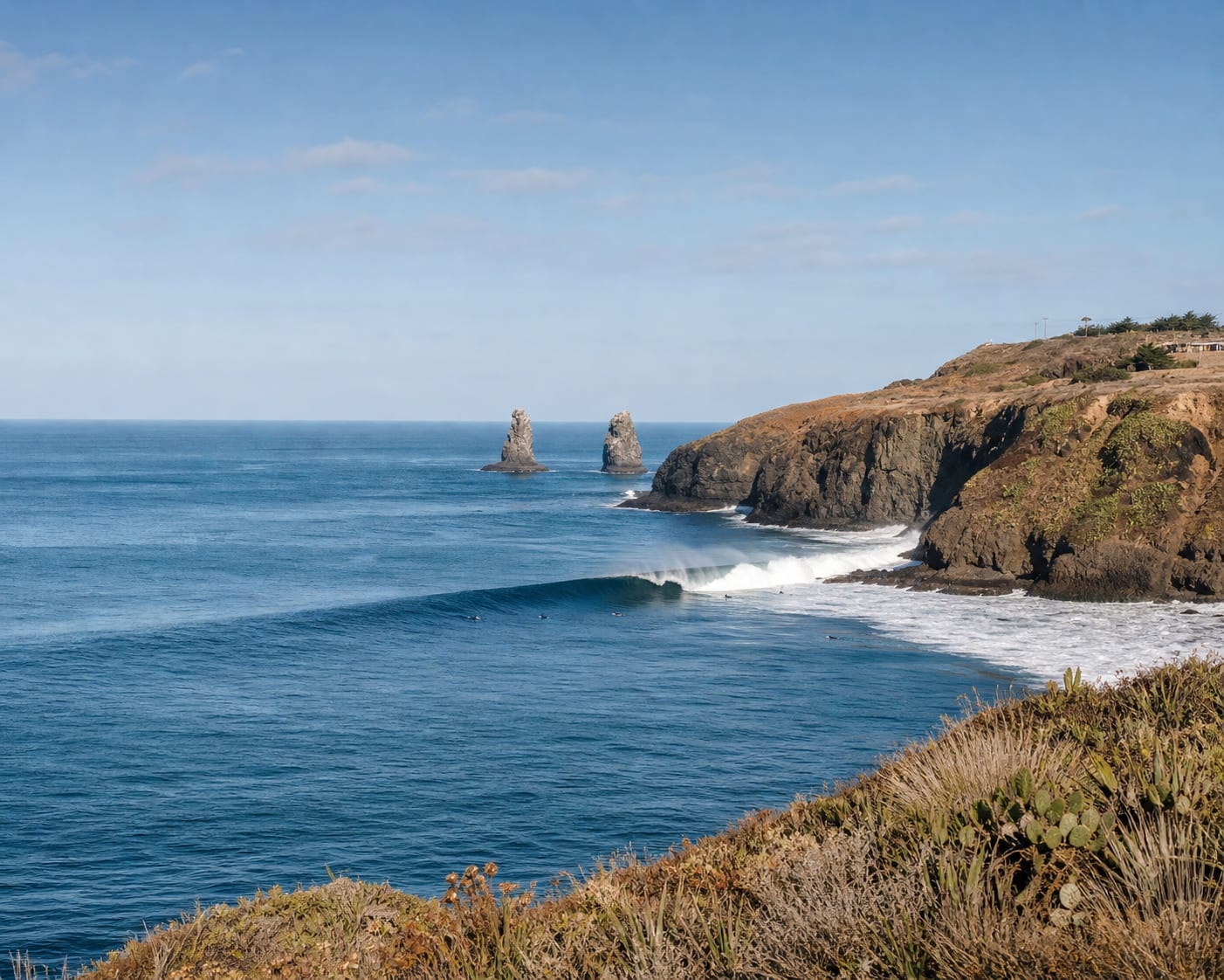 Punta de Lobos surf curling beneath its cliffs and twin sea stacks
