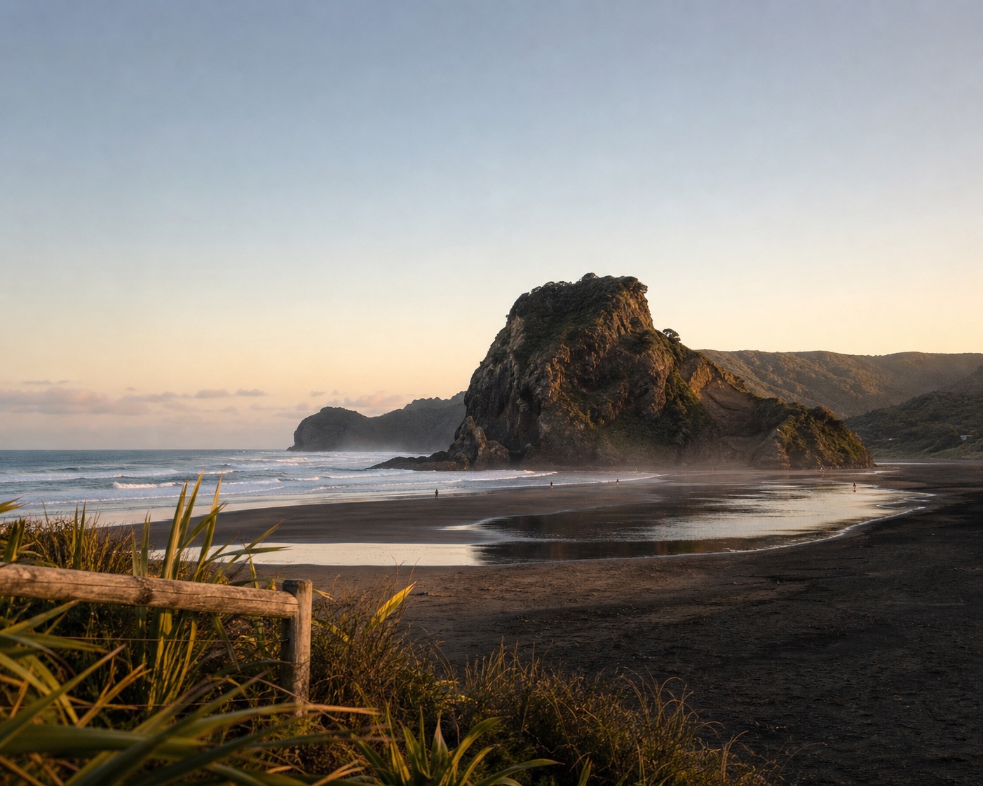 Lion Rock rising from Piha's black sand beach in late-afternoon light