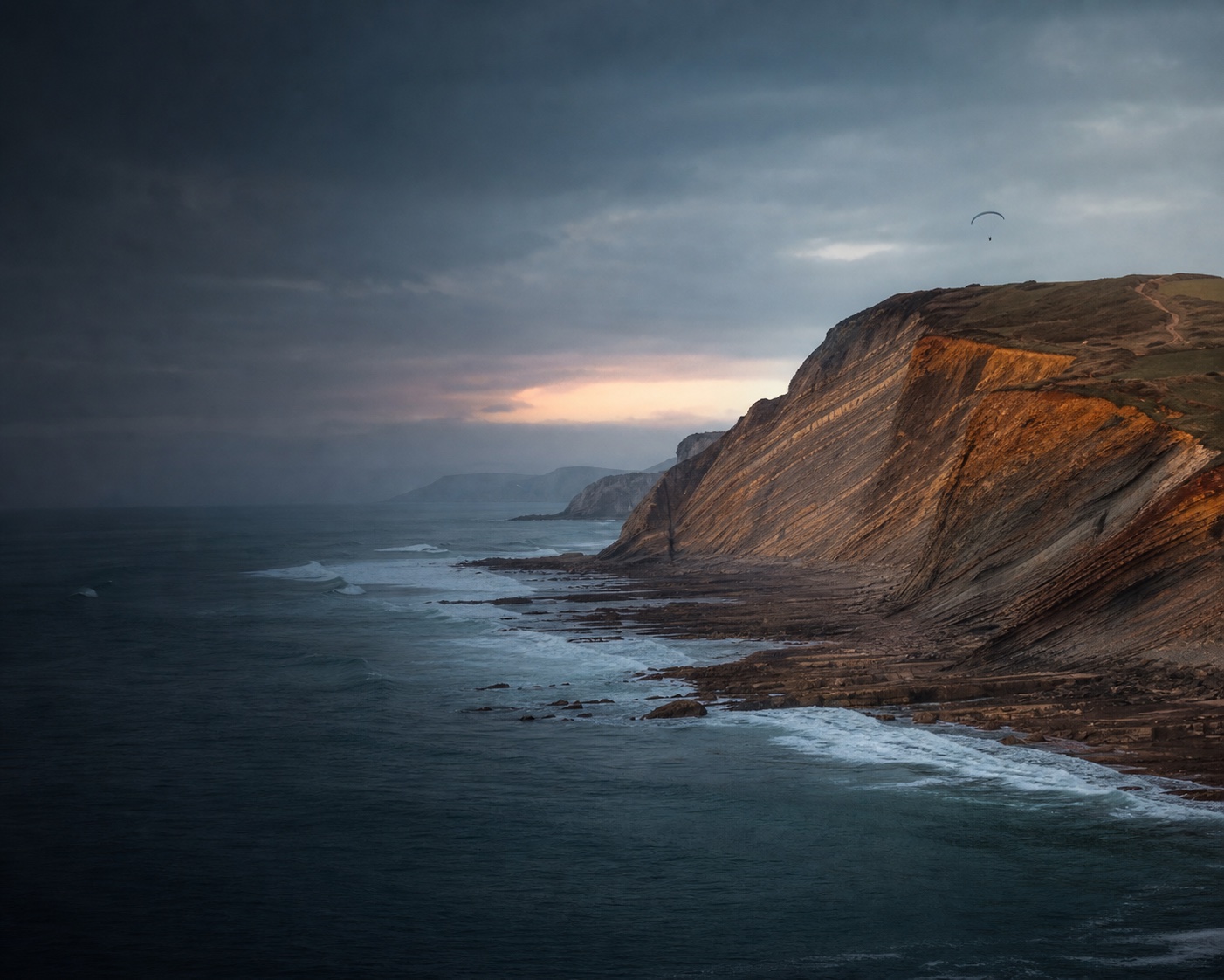 Sopela surf beneath the tilted layers of its ochre flysch cliffs